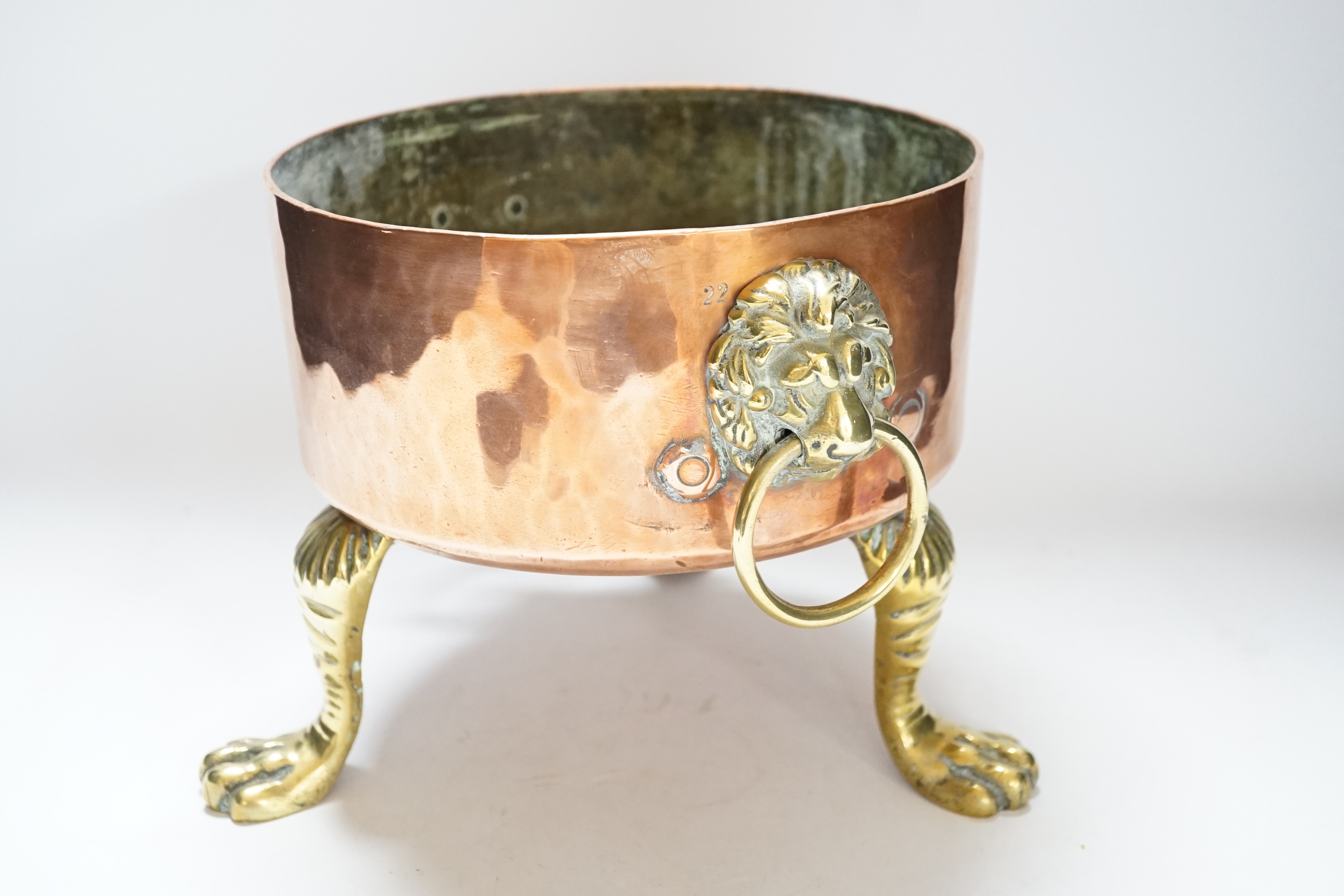 A heavy copper planter or cooking pot, with cast brass lion mask and ring handles, on brass claw feet, 20cm high